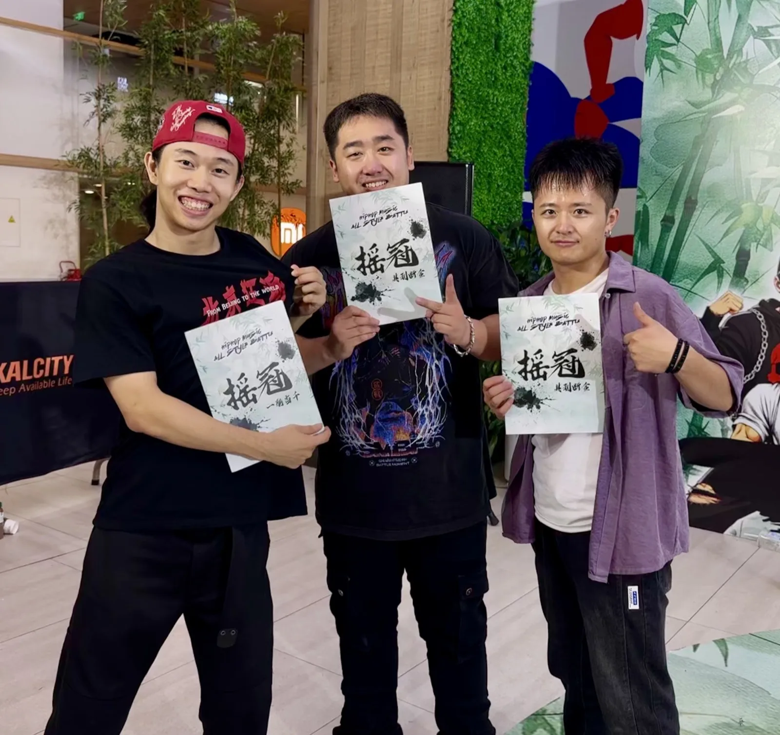 扎飞与两位队友在台前举着摇霸 all style battle 的奖状合影